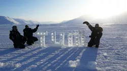 TUM students next to the ice sculpture of the TUM logo they created