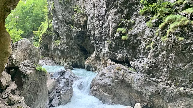 View of turquoise stream and green rock walls in the Partnach gorge