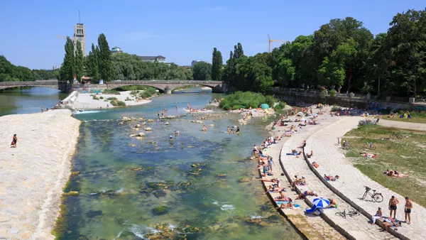 On a hot summer day, numerous people enjoy the sun on the banks of the Isar River