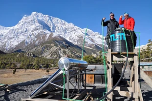  Two members of the TUM project team in Nepal  pose proudly in front of their self-built solar warm water collector