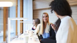 Aalto-Mitarbeitende und Gäste sitzen mit ihren Laptops um einen Tisch