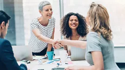 Three women and one man handshaking on a business meeting