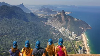 Studierende der TUM mit Caps der Uni genießen bei ihrem Auslandsaufenthalt in Brasilien den Ausblick auf Berge, Wälder und das Meer