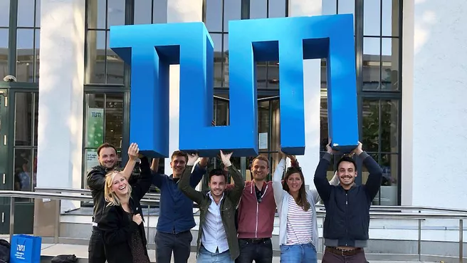 Mitglieder der TUM-Community mit großem TUM-Logo. Bild: Sebastian Bartsch