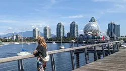 Frau blickt von Steg auf die Skyline einer Großstadt am Wasser