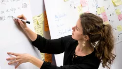 Frau schreibt Notizen auf ein Flipchart