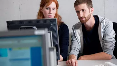 A man and a woman sitting side by side in front of a computer