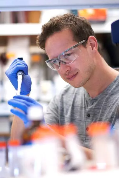 [Translate to en:] Matthias Pauthner pipettiert HIV DNA aus einem Eppendorf Reaktionsgefäß im Burton Labor. (Bild: Westley Dang, TSRI)