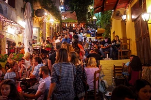 Various people enjoy a beautiful summer night in terraced restaurants in Athens