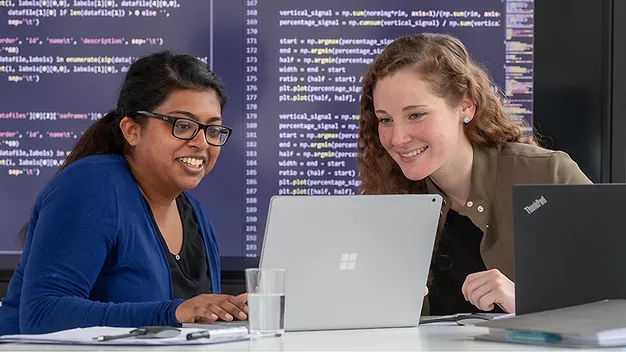 Two female students working on a laptop