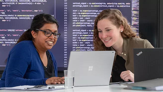 Two female students working on a laptop