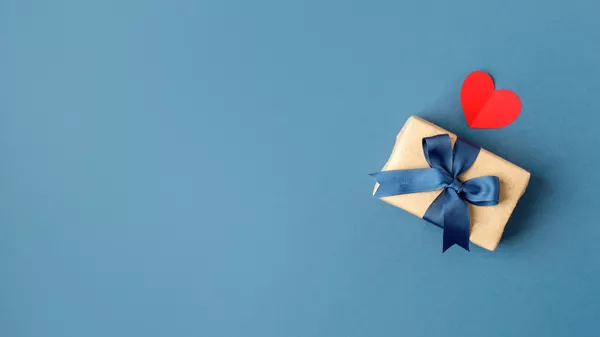 Geschenk-Box mit blauer Schleife und ein rotes Herz auf blauem Hintergrund 