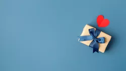 Geschenk-Box mit blauer Schleife und ein rotes Herz auf blauem Hintergrund 