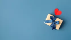 Gift box with blue bow and a red heart on blue background