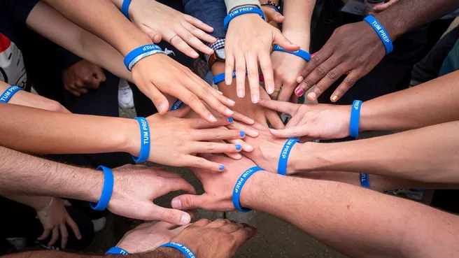 Hände von Teilnehmenden mit verschiedenen Hautfarben mit TUM PREP-Armbändern