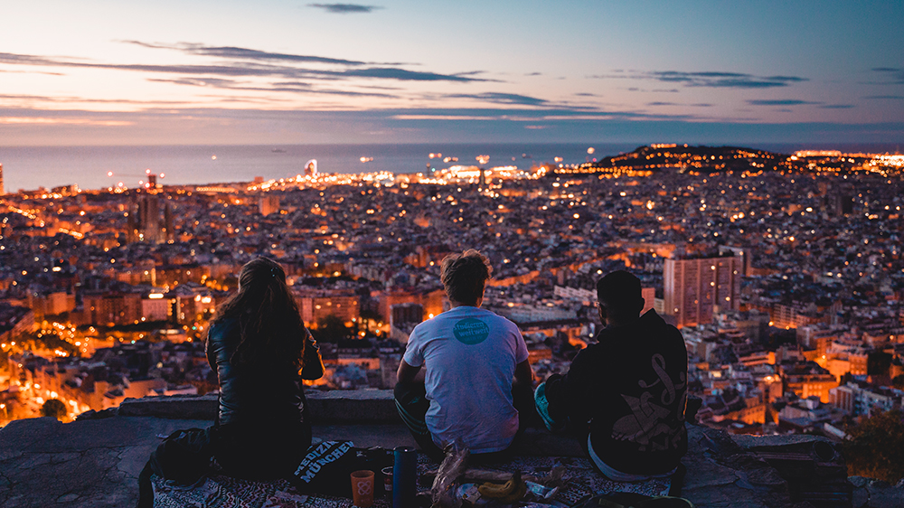 Drei Studierende genießen den Ausblick auf Barcelona bei Sonnenaufgang