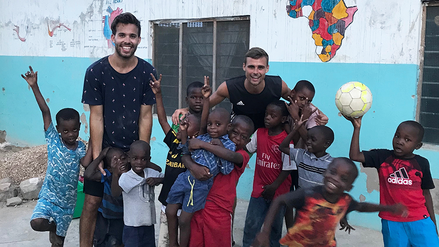 Zwei Studierende der TUM spielen mit Kindern auf Sansibar Fußball