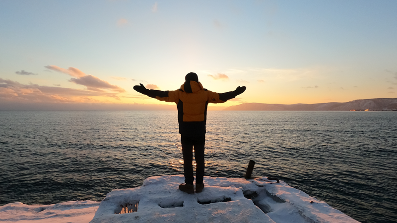 Man with outstretched arms on frozen lake
