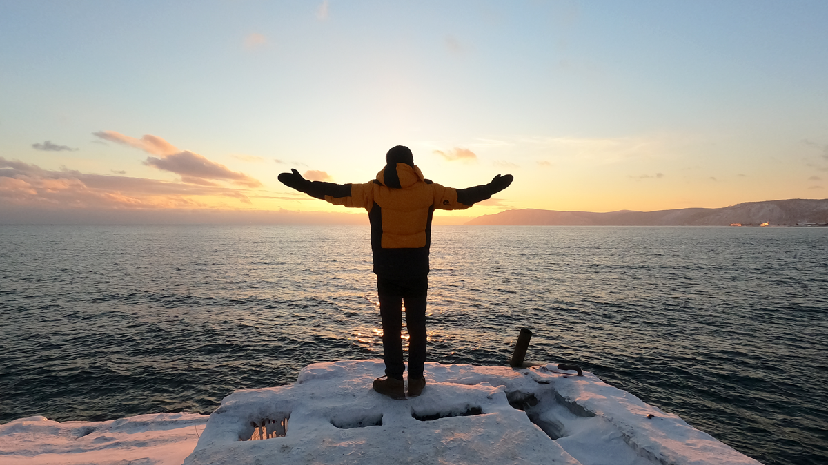 Man with outstretched arms on frozen lake