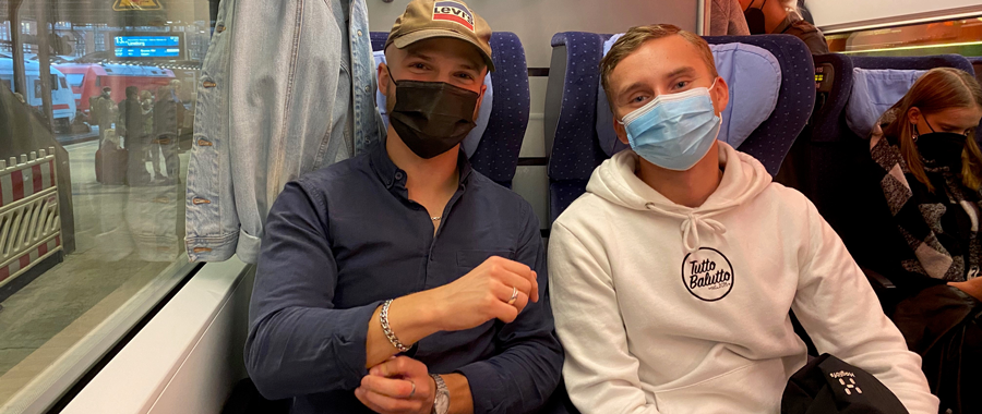 Zwei Studenten mit Gesichtsbedeckung in einem Zug