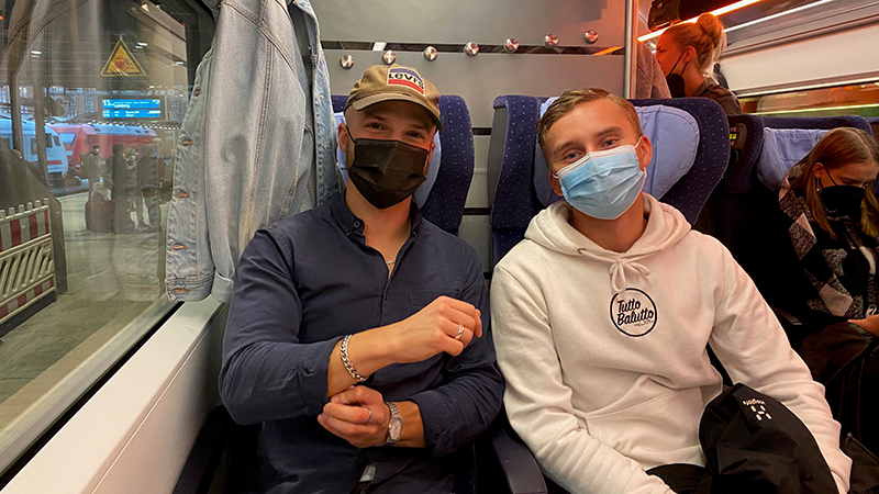 Two students with face coverings in a train