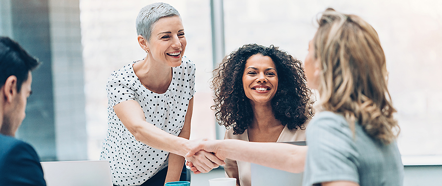 Three women and one man handshaking on a business meeting