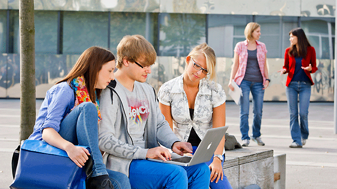 Drei Studierende der TUM recherchieren am Laptop im Außenbereich des Campus Garching.