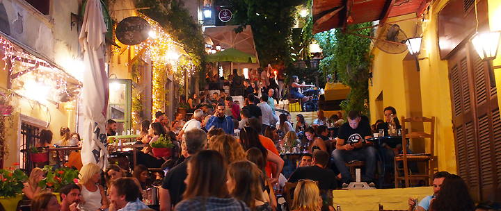 Zahlreiche Menschen genießen einen schönen Sommerabend in terrassenförmig angelegten Restaurants inmitten Athens