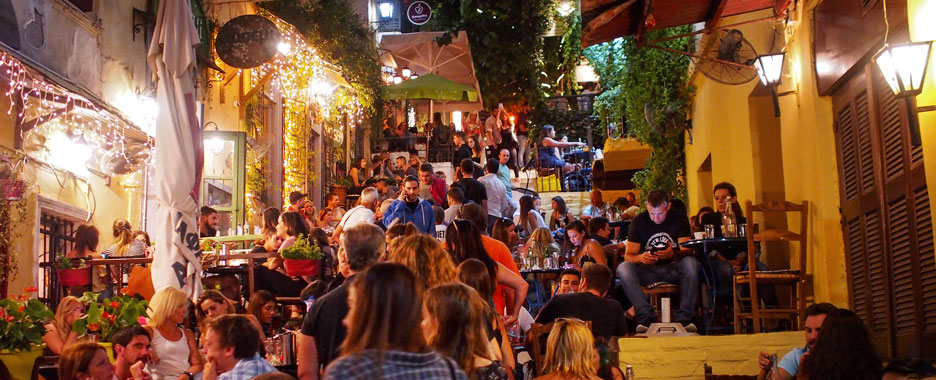 Zahlreiche Menschen genießen einen schönen Sommerabend in terrassenförmig angelegten Restaurants inmitten Athens