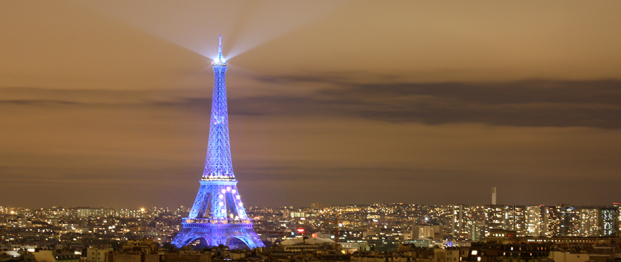 Blau leuchtender Eiffelturm mit Eurozeichen im nächtlichen Paris