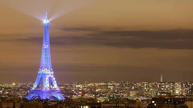 Blue glowing Eiffel Tower with euro sign in Paris at night